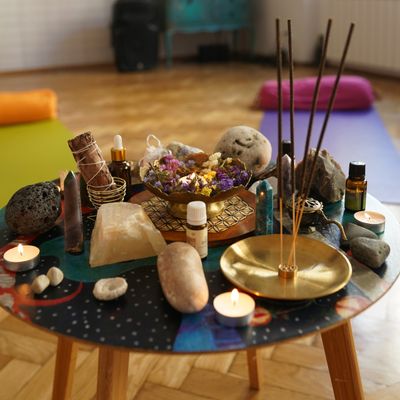 A meditation altar with crystals, candles, incense, and essential oils on a colorful table.