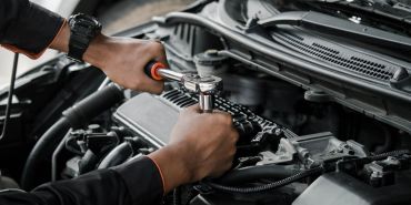 Person fixing car engine with a wrench.