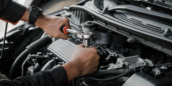 Close-up of hands fixing a car engine with a ratchet wrench.