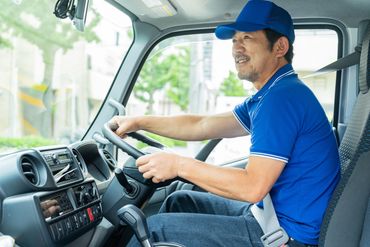 Smiling man in blue shirt and cap driving a vehicle safely with a seatbelt.