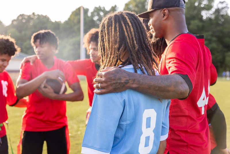 Coach huddles with high school flag football team on sidelines of game