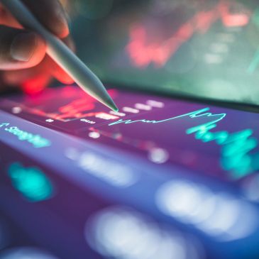 Stylus pointing at glowing financial chart on tablet screen.