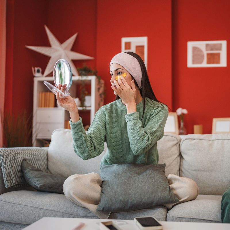 Relaxing at home. One woman enjoying her skincare beauty routine while sitting on the couch. Cozy domestic atmosphere modern interior everyday lifestyle moment