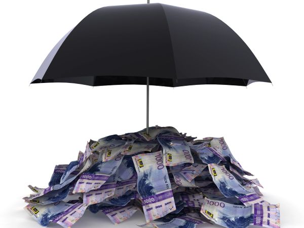 Black umbrella shielding a pile of 1000 Norwegian krone bills.