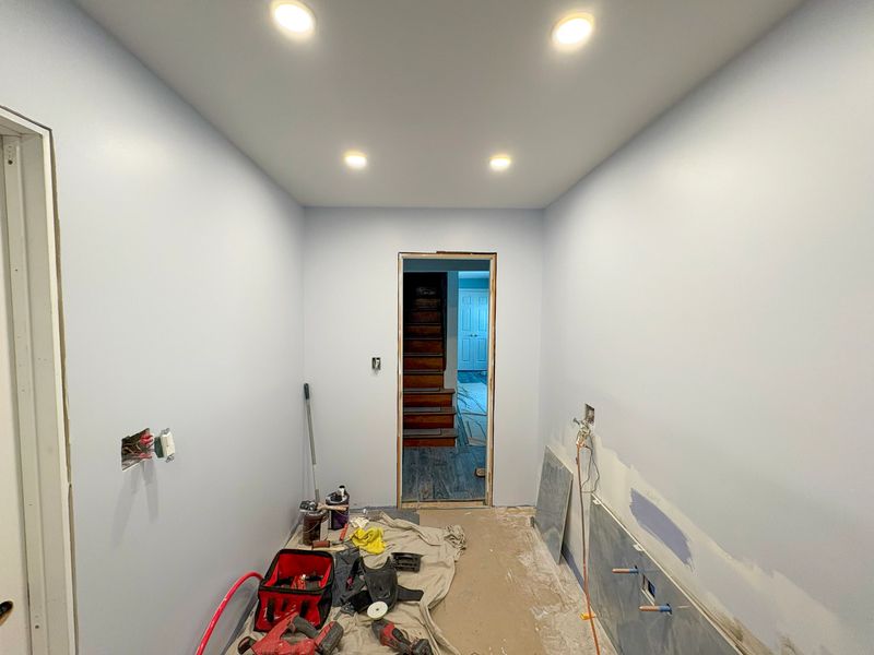 Bathroom undergoing renovations with newly painted walls and modern lighting.