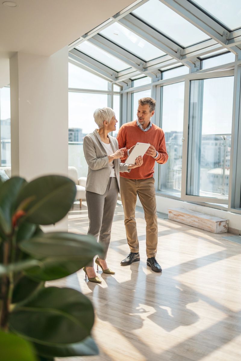 Business colleagues engage in a professional discussion, reviewing documents within a bright and modern office. The natural lighting and collaborative atmosphere emphasize teamwork, clarity, and professional interaction in a corporate environment.