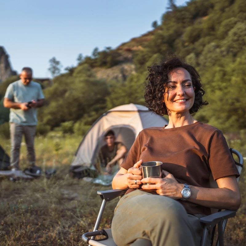mature woman hold cup and enjoys camping with her family