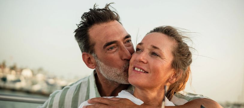 Man kissing woman on the cheek outdoors.