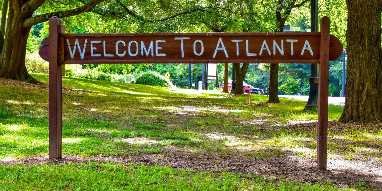 A wooden sign saying 'Welcome to Atlanta' in a park.