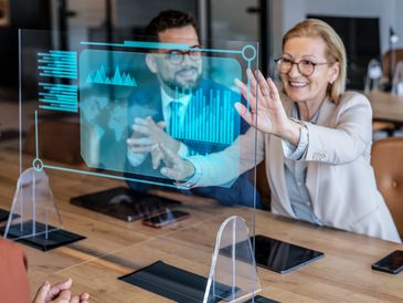 Business professionals interacting with a futuristic transparent digital display in a meeting.