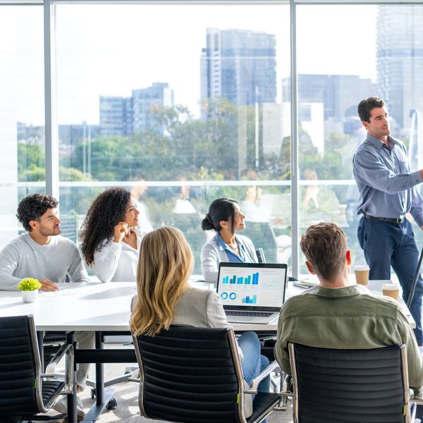 Business team attending a presentation in a bright office with city views.