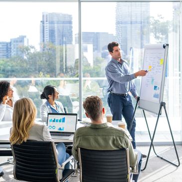 A man presents data to colleagues in a modern office meeting.