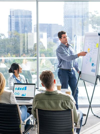 Business meeting with a man presenting data on a flip chart to colleagues.