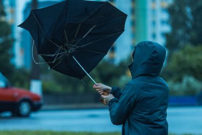 Person struggling with an inverted umbrella in the wind.