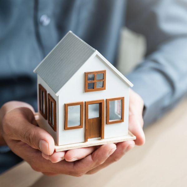 Person holding a small model house in their hands.