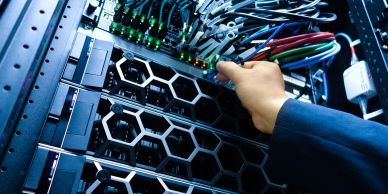Mão conectando cabos em hardware de servidor.