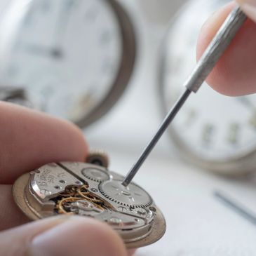 Close-up of hands repairing a mechanical watch with precision tools.