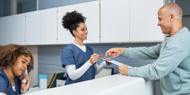Receptionist handing a pen to a man at the front desk.