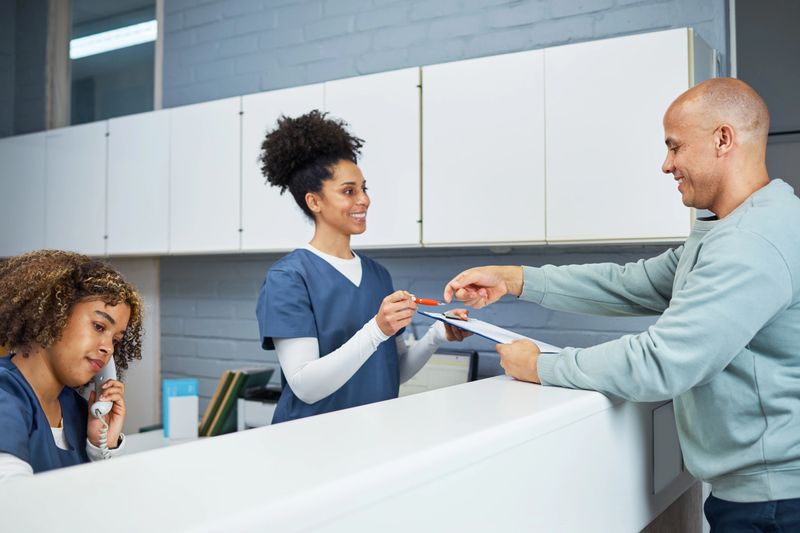 Dentists' office reception area featuring professional staff in uniform assisting a patient. Emphasizing excellent customer service and efficient healthcare management in a clean and organized environment.