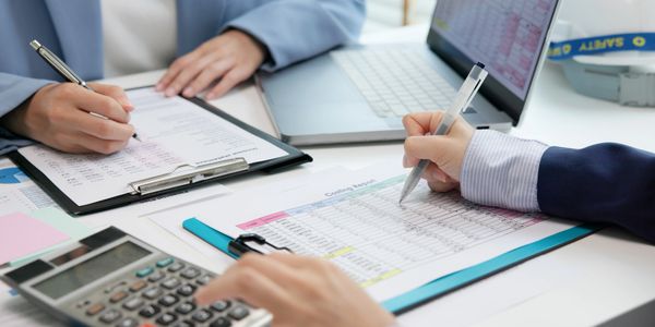 Two professionals review financial documents and use a calculator at a desk.