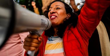 Woman passionately speaking through a megaphone at a protest.