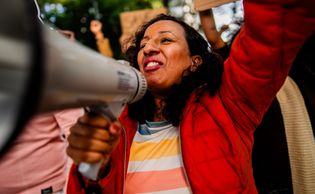 Woman passionately speaking through a megaphone at a protest.