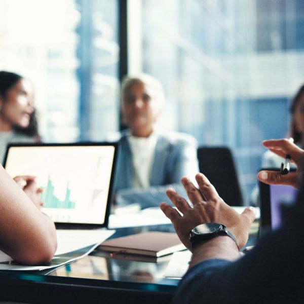 Business meeting with people discussing data on laptop.