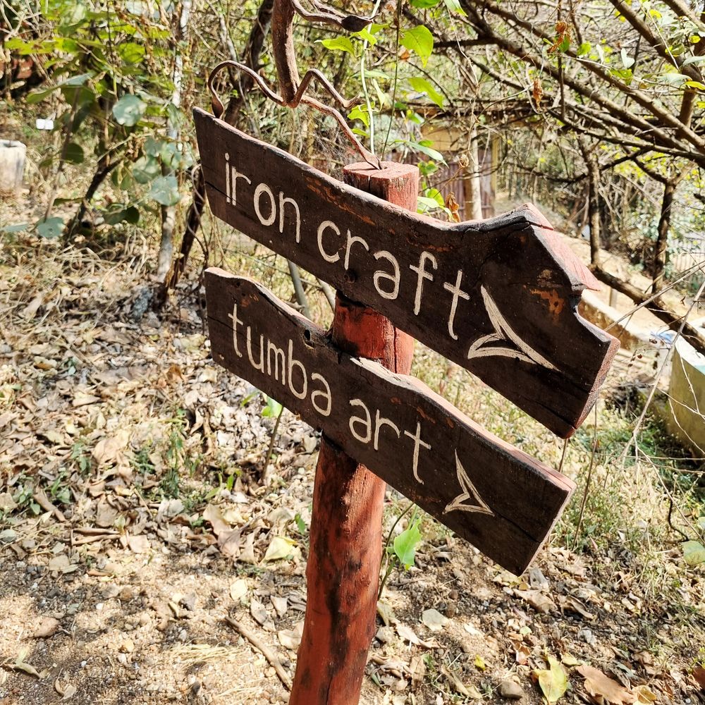 Wooden signpost in nature pointing to iron craft and tumba art.