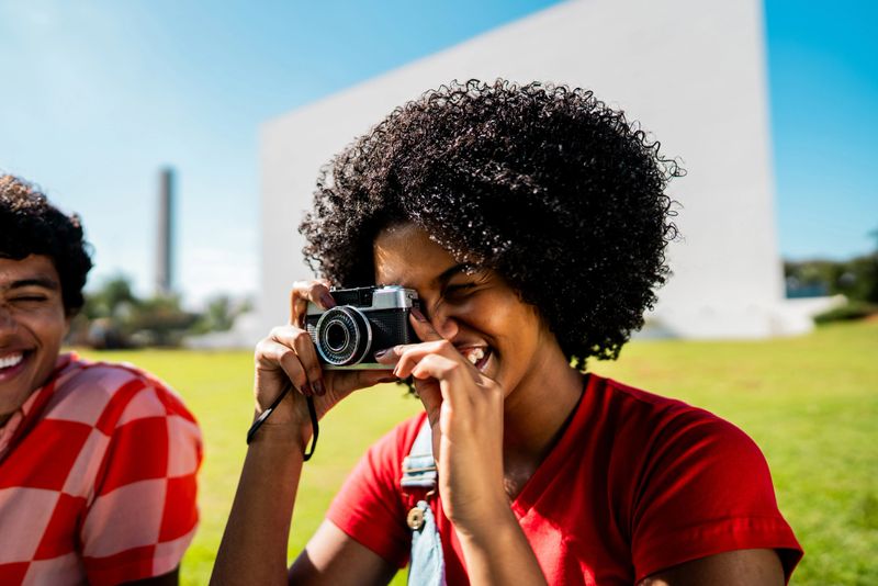 Young woman photographing using camera on public park
