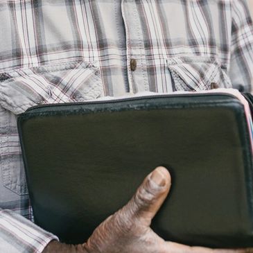 Person holding a black leather wallet or case.