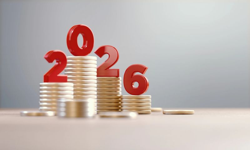 Red 2026 on coin stacks before defocused background. Horizontal composition.