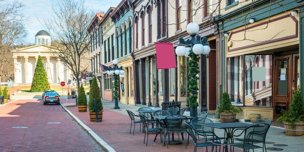 Quaint street with outdoor café seating and festive holiday decorations.