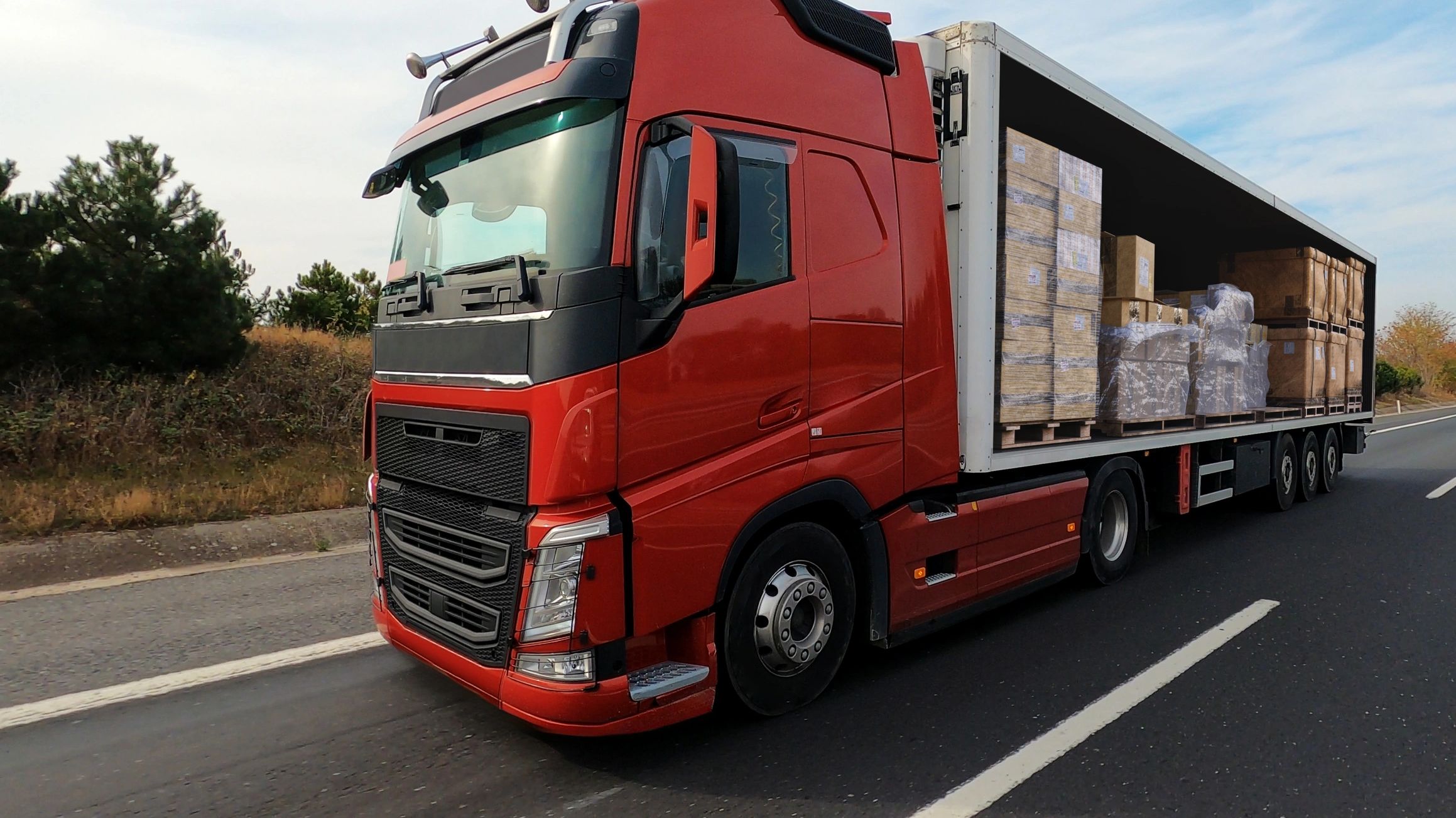 Red semi-truck transporting cargo on a highway.