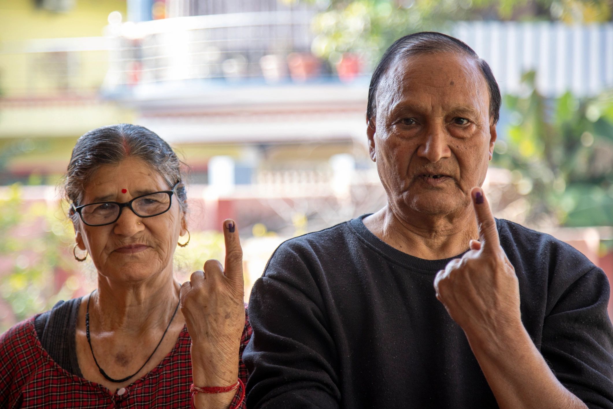 Close-up of an elderly Indian couple proudly showing their ink-marked fingers after casting their votes. Smiling at the camera, they reflect civic pride, unity, and democratic participation in rural India.