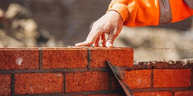 A worker laying bricks and smoothing mortar on a wall.
