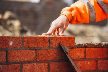 Worker laying bricks on a wall.