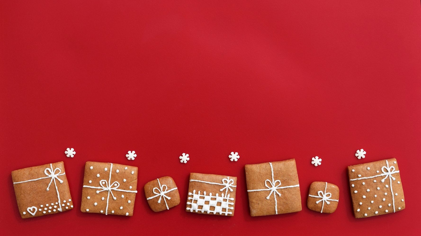 Gingerbread cookies decorated like wrapped gifts on a red background.