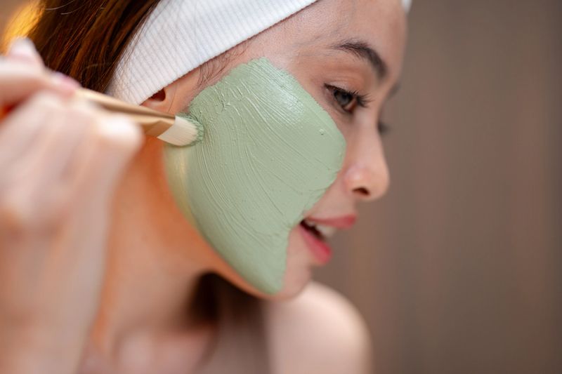 Young woman making organic face mask at home, blending natural ingredients in a small mixing bowl, combining fresh, eco-friendly components, creating a rejuvenating treatment tailored to her skin's needs, reflects her commitment to self-care and using sustainable products that nourish her skin and connect her to nature