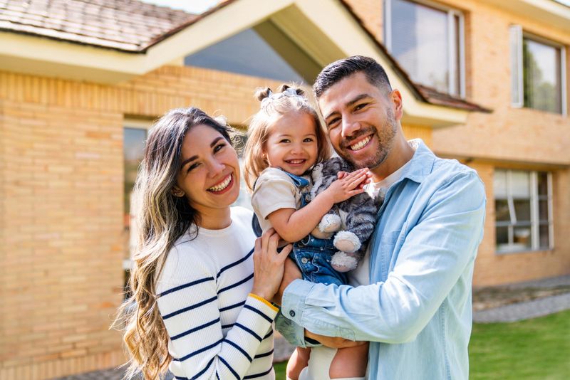 Happy Latin American family smiling outside their house and looking at the camera