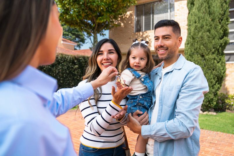 Real estate agent giving the keys of their new house to a happy Latin American family - home ownership concepts
