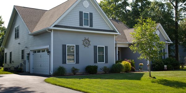 PIC OF SUBURBAN HOME REPAINTED THE COLOR SILVER GRAY WITH A GREEN LAWN AND TREE