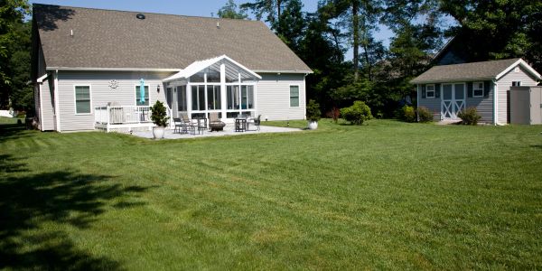 House with a large green lawn and two sheds.