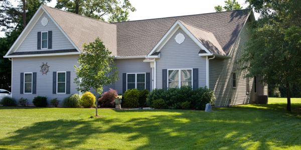 A gray house with a well-maintained green lawn and trees.