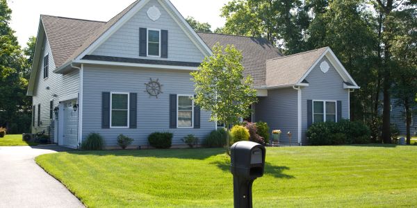 A blue suburban house with a mailbox and green lawn.
