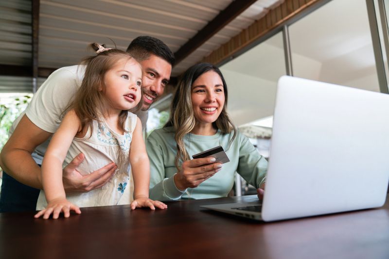 Happy Latin American family shopping online from home and paying by credit card - e-commerce concepts