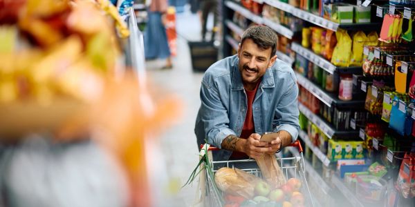 Man shopping with a cart filled with groceries.
