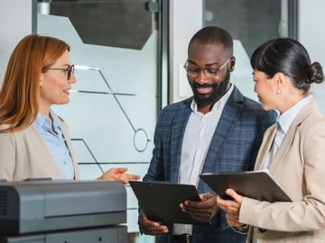 Three professionals discussing documents in an office setting.