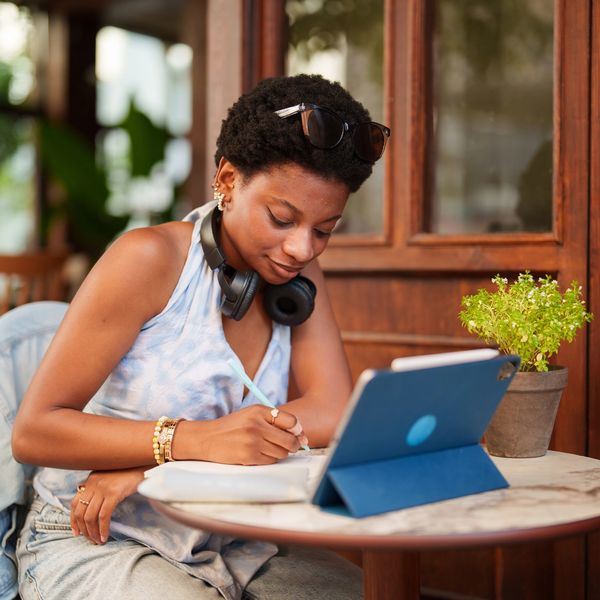 Woman studying with tablet and notebook at a café.
