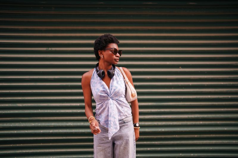 A young woman posing naturally against a striped background, reminiscent of a fashion model. Her relaxed and confident demeanor captures moments of casual elegance in a studio-like setting.
