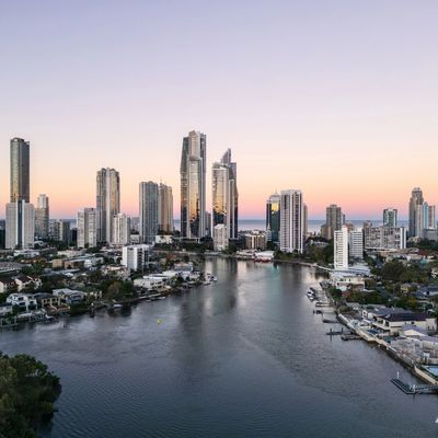City skyline with tall buildings along a river at sunset.